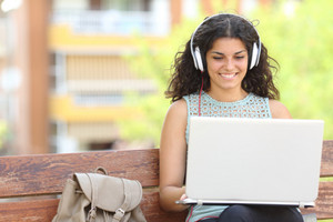 Studentin mit Kopfhörer und Laptop am Schoß