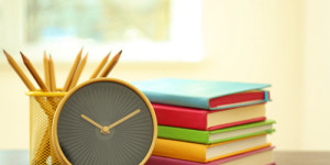 5 stacked books in different colors, pencil holder and alarm clock