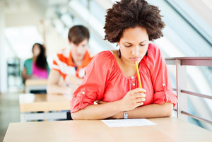 Female student at exam, bent over leaf in pensive pose