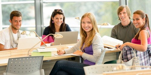 6 Studierende in hellem Unterrichtsraum blicken lächelnd in Richtung Kamera