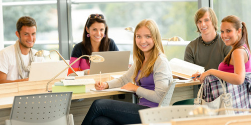 6 Studierende in hellem Unterrichtsraum blicken lächelnd in Richtung Kamera