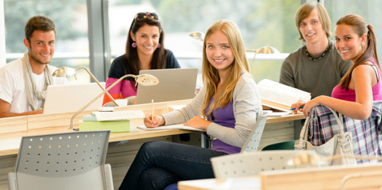 6 Studierende in hellem Unterrichtsraum blicken lächelnd in Richtung Kamera