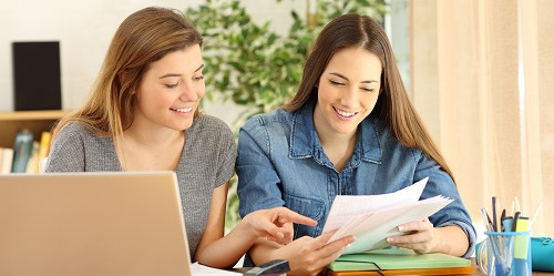 Schreibtutorinnen Zwei weibliche Studierende über Laptop und Text gebeugt im Austausch