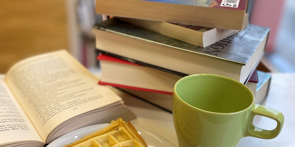 Bücher auf Tisch, Waffel und Tasse