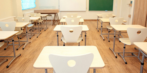 Classroom with empty white tables and chairs