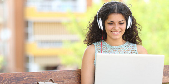 Self-learning Student with headphones and laptop on lap
