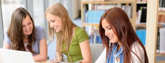 3 female students sit around a table and study together