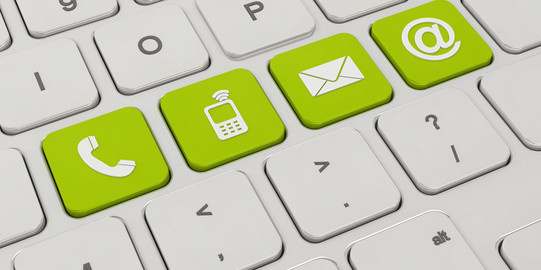 Auf einer weißen Tastatur sind vier Tasten grün eingefärbt. Darauf zu sehen sind Symbole für ein Telefon, ein Mobiltelefon, ein Briefumschlag und ein "at"-Zeichen.