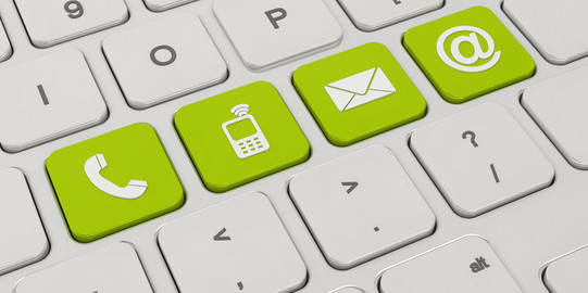 Auf einer weißen Tastatur sind vier Tasten grün eingefärbt. Darauf zu sehen sind Symbole für ein Telefon, ein Mobiltelefon, ein Briefumschlag und ein "at"-Zeichen.